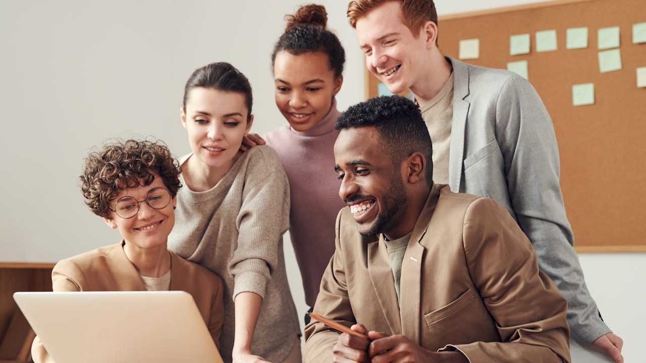 A team collaborating around a table in a modern office — representing the payment-technology company Network Merchants, Inc.