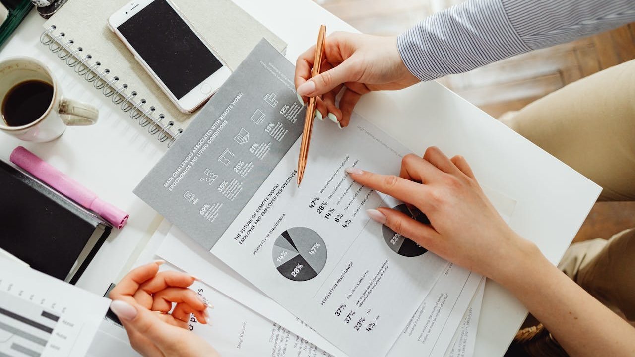 Two people reviewing transaction reports and charts at a desk — representing the Merchant Central reporting and dashboard view