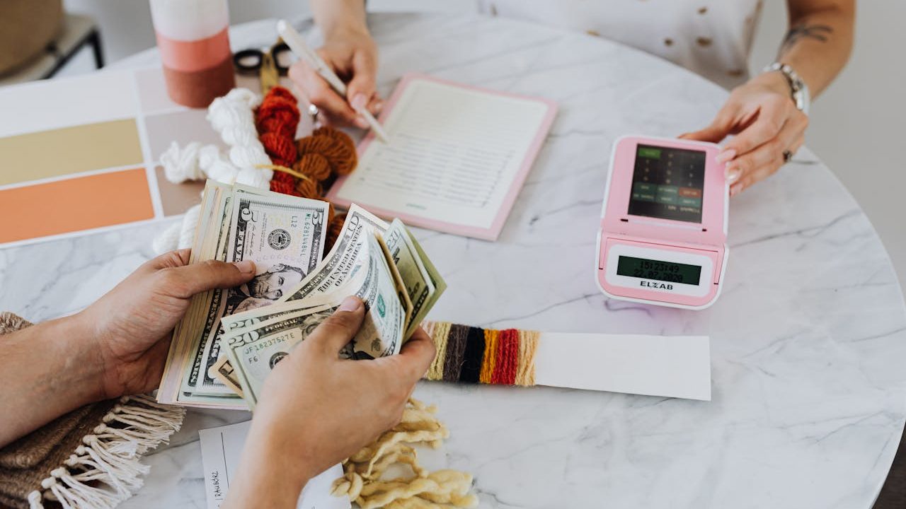 A hand holding US bank notes beside a card payment terminal on a counter — illustrating how the NMI gateway connects card acceptance to a processor